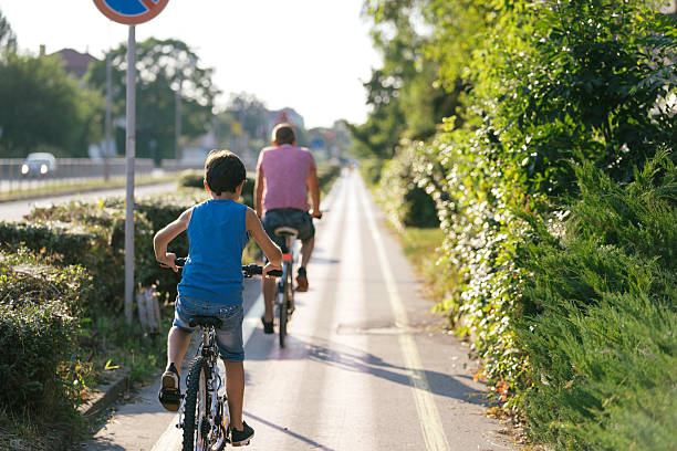 A happy child and adult biking side by side along a scenic pathway, surrounded by greenery, enjoying a sunny day in the park, conveying joy and connection.