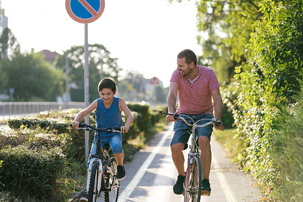 istock Father and son riding bicycles in sunny park 2207964582