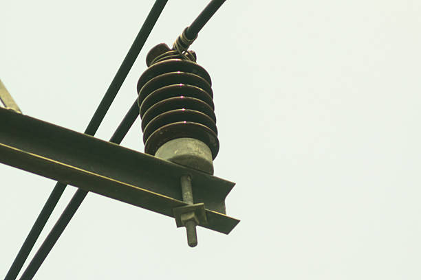 Close-up view of a power line insulator against a clear sky. This image showcases electrical infrastructure, highlighting the insulator's design and function.