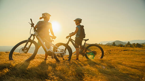 istock Female Cyclists Resting with E-Bikes at Mountain Overlook During Sunset 2207965092