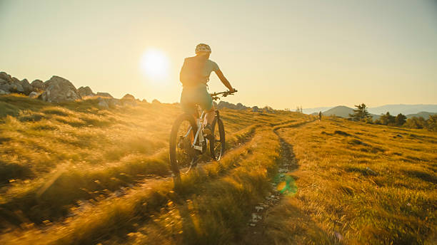 istock Female Cyclist Riding Uphill on a Mountain Trail at Sunset 2207965095