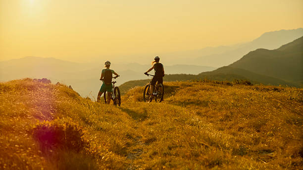 istock Female Cyclists Resting with E-Bikes at Mountain Overlook During Sunset 2207965100