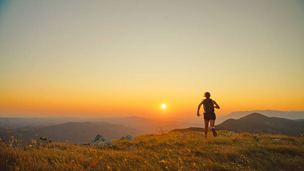 istock Solo Female Runner Silhouetted on Mountain Ridge at Sunset 2207965255