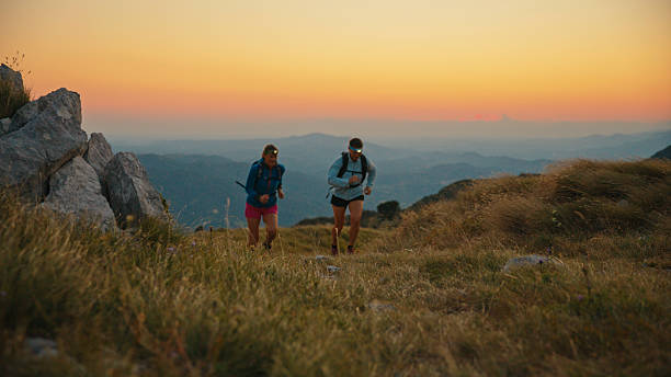 istock Female Runners Ascend Mountain Trail with Forehead Flashlights at Dusk 2207965266