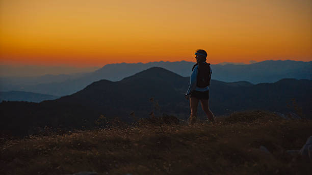 istock Solo Female Hiker with Headlamp on Mountain Overlook at Twilight 2207965281