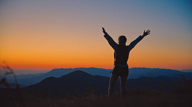 istock Woman Celebrates Reaching Mountain Peak at Dusk 2207965299