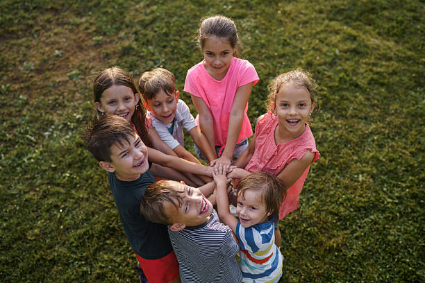 Children playing games with their teacher in a circle at school playground