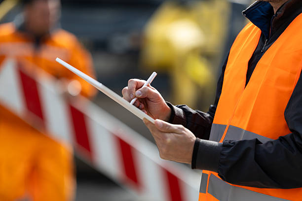 istock Construction worker in safety vest taking notes at a worksite during daytime 2207965846