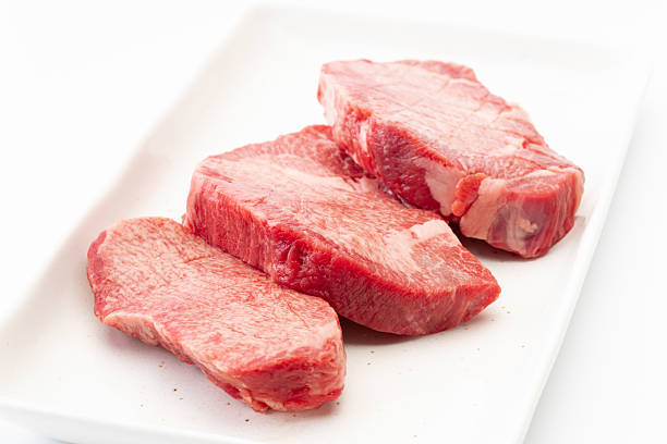 Meat raw steaks lie on a black background with vegetables, tomatoes, marasmade, mushrooms. background