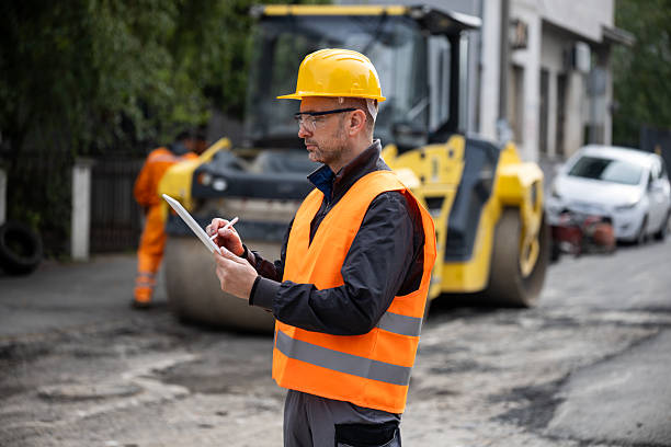 istock Construction manager oversees road maintenance project while noting details on clipboard in urban setting 2207966164