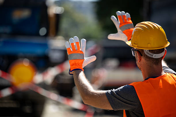 Construction worker directing traffic at a busy site in the afternoon under clear skies during ongoing repair work