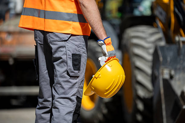 istock Worker in safety gear holds yellow hard hat on construction site during daylight 2207966348