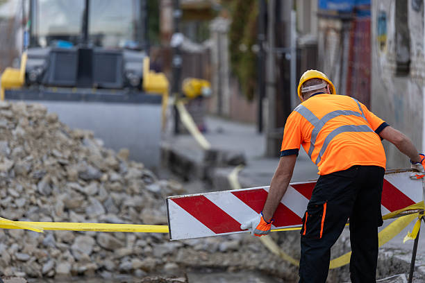 istock Construction worker sets up traffic barrier on street under renovation while machinery operates in background 2207966375