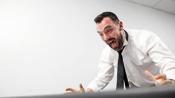istock An enraged office worker smashes a computer monitor with his keyboard. 2207969468