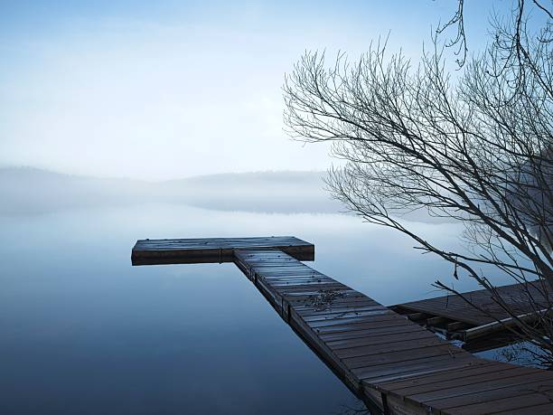 A landscape photo of a wood dock on the calm early morning water of Hauser Lake in Idaho.