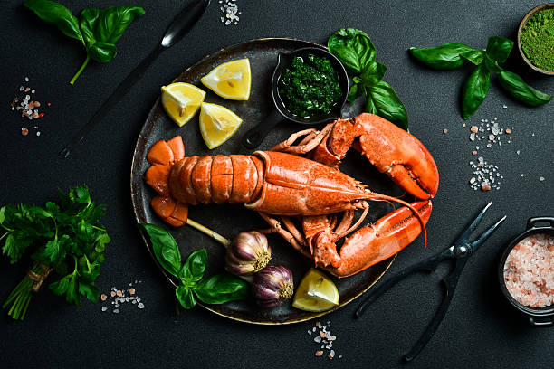 istock Luxurious boiled spiny lobster with spices, basil and lemon on a black stone plate. Free space for text. 2207974097