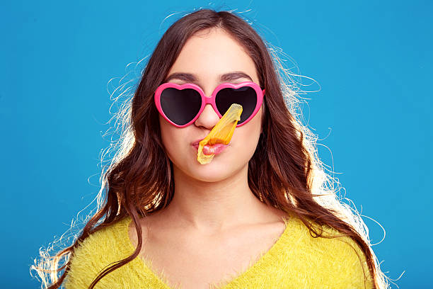Beautiful young girl blowing bubble with chewing gum on blue background
