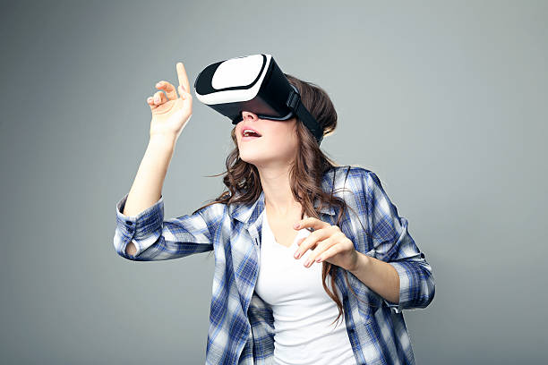 istock Young girl in virtual reality goggles on grey background 2207976599