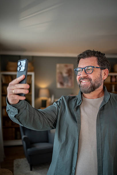 istock Smiling man taking a selfie with smartphone at home 2207978254