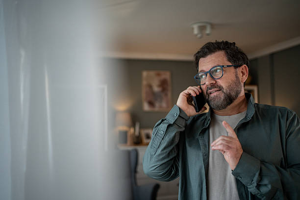 istock Mature man talking on the phone at home explaining something 2207978311