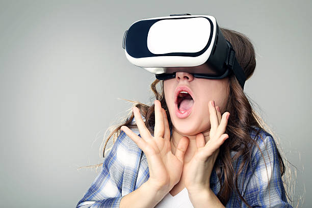 istock Young girl in virtual reality goggles on grey background 2207978538