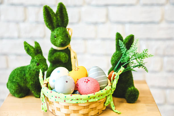 istock Colorful Easter eggs and decorative bunnies arranged in a basket on a wooden table 2207978906
