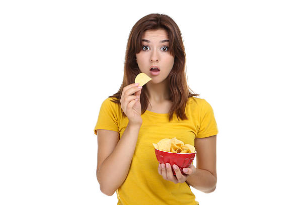 istock Young woman with potato chips in bowl on white background 2207978973