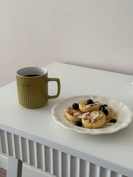 Enjoy a delightful breakfast of fluffy pancakes topped with fresh blueberries and crunchy almonds and cup of coffee on white plate.