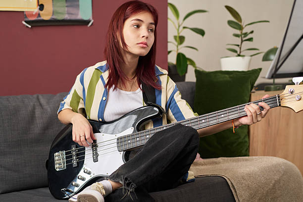 istock Contemplating While Holding Electric Bass Guitar on Couch 2207980808