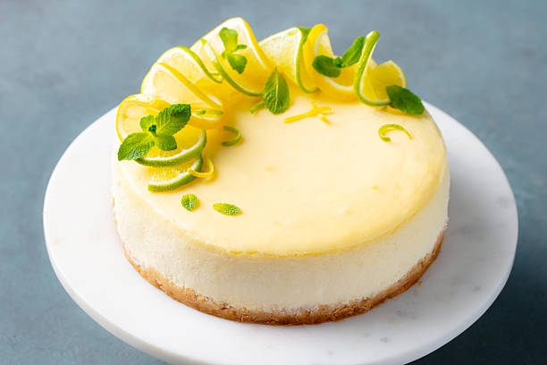 istock Lemon cheesecake garnished with fresh lemon, lime and mint on a white plate. Grey background. Close up. 2207983115