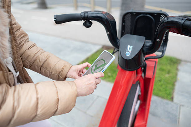 istock Woman unlocking a shared electric bike with her smartphone app 2207983408