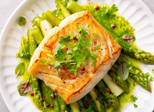istock Fried cod with asparagus and on plate. Grey background. Close up. Top view. 2207983823