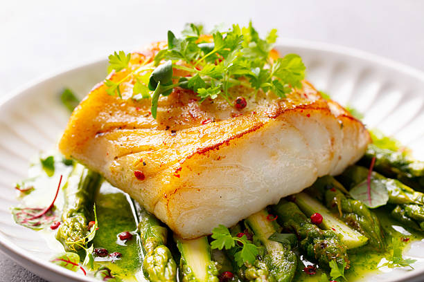 istock Fried cod with asparagus and on plate. Grey background. Close up. 2207983854