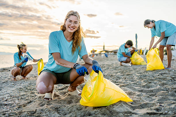 istock Young female volunteer cleaning a polluted beach 2207984073