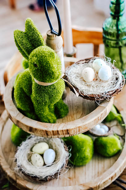 istock Green bunny decoration with eggs displayed on wooden tiered tray in spring setting 2207984210