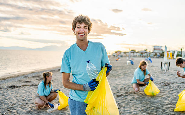 istock Young male volunteer cleaning a polluted beach 2207984226