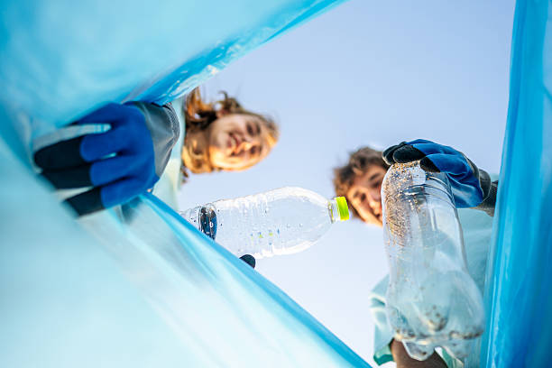 istock Young volunteers putting plastic bottles in a trash bag 2207984516