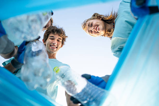 istock Young volunteers putting plastic bottles in a trash bag 2207984578