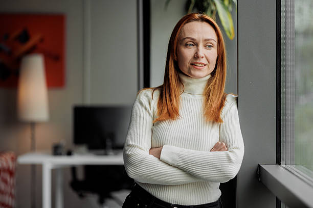 istock Content woman looks out office window 2207987054
