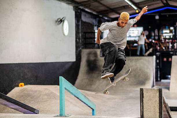istock Young man doing skateboard trick over rail at indoor park 2207990272