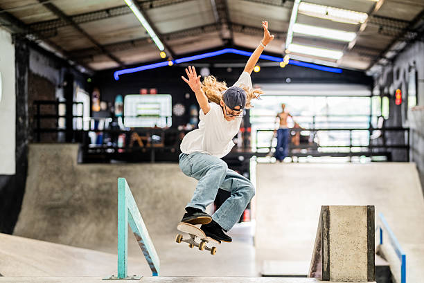 istock Young woman doing skateboard trick over rail at indoor park 2207990290