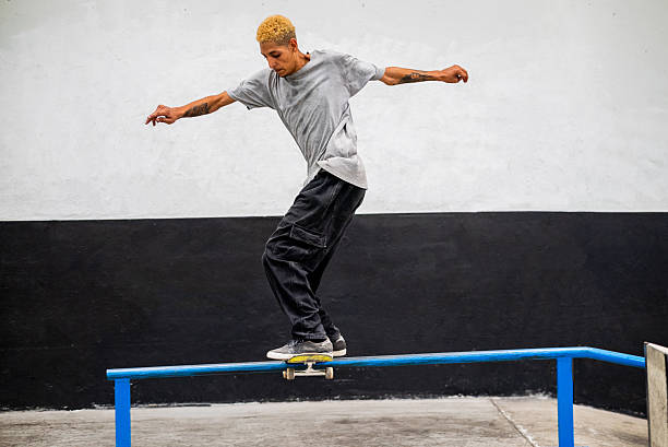 Young man doing skateboard trick over rail at indoor park
