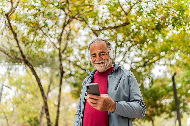 istock Senior man walking and using mobile phone on public park 2207991126