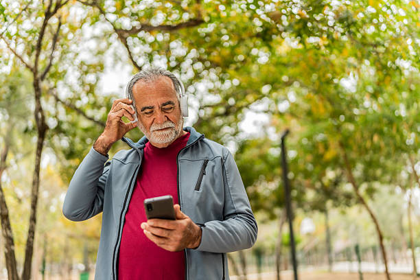 istock Senior man walking and using mobile phone on public park 2207991138