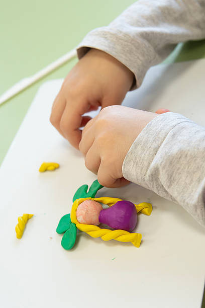 a child plays with plasticine and makes a doll