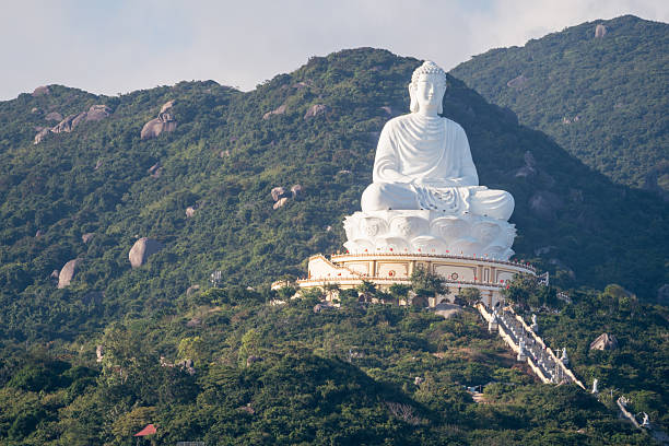 A majestic white Buddha statue perched atop a lush green mountain, symbolizing peace and tranquility.