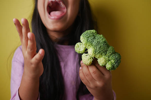 istock Child Playfully Reacting to Broccoli Under a Yellow Background 2207999044