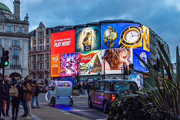 London, UK - December 10 2025: hoarding with advertising screens installed around the Shaftesbury Memorial Fountain, aka Eros, in Piccadilly Circus, with incidental people walking.