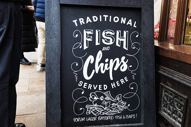 Traditional British fish and chips sign displayed on a chalkboard outside a restaurant, promoting fresh food. London, UK, 17 December 2023