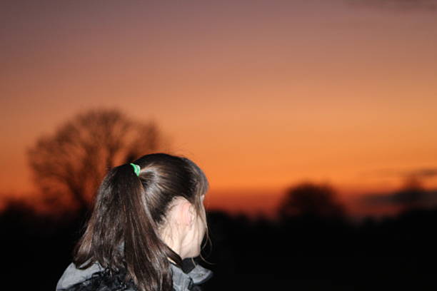 Brown haired woman looking off into the beautiful orange/red sunset